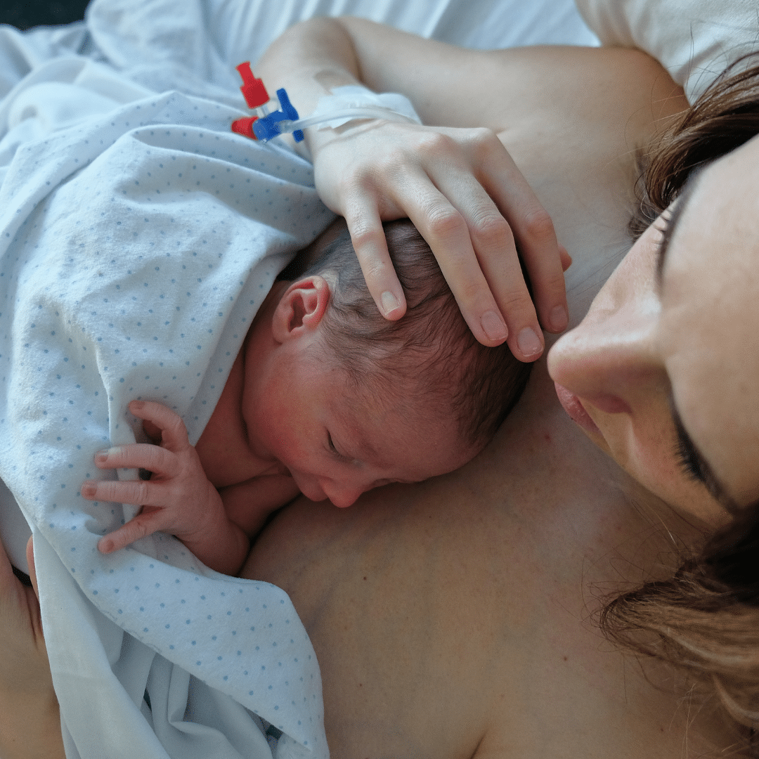 Mum cuddling newborn baby after birth.